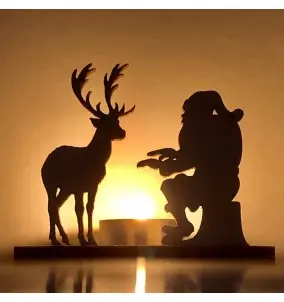 Svečnik božiček in jelen se grejeta ob ognju - spredaj s prižgano svečko