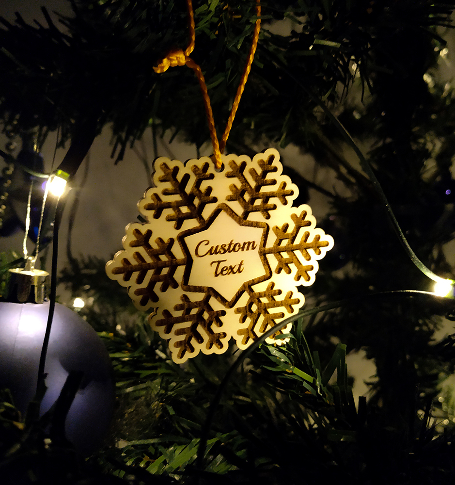 Hölzerne Schneeflocke mit Text auf einem Weihnachtsbaum.